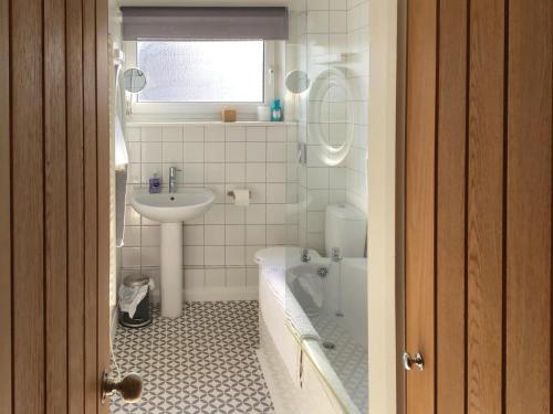a bathroom with a sink and a tub and a toilet at Waters Edge Holiday Home in Beadnell