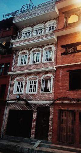 a red brick building with white windows on a street at Nirvana Kuti in Kathmandu