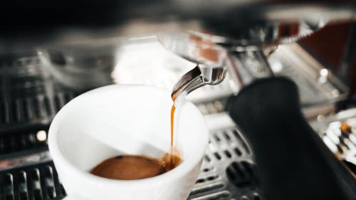 a coffee being poured into a cup in a machine at Into the town krabi in Krabi town