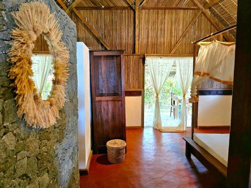 Cette chambre comprend un lit et un mur avec des fenêtres. dans l'établissement KINTANA LODGE, sur l'île aux Nattes