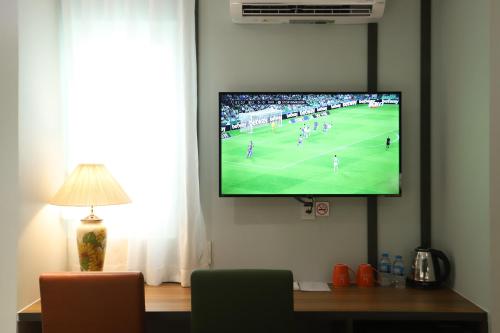 a tv hanging on a wall with a soccer game on it at Lanura Apartments and Hotel in Ho Chi Minh City