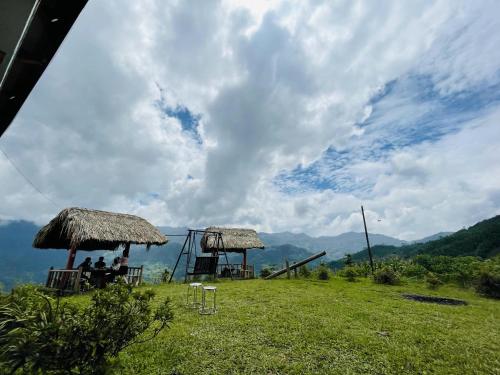 two people sitting in chairs under umbrellas on a hill at Homestay Chân Mây Chiêu Lầu Thi in Hoàng Su Phì
