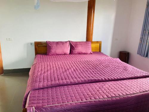 a bed with a pink comforter in a bedroom at Homestay Chân Mây Chiêu Lầu Thi in Hoàng Su Phì