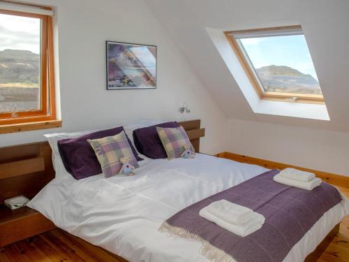 a bedroom with a bed with two pillows and two windows at Seascape in Fiskavaig