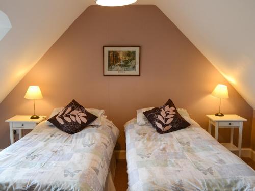 two beds in a attic room with two lamps at An Sealladh in Lochinver