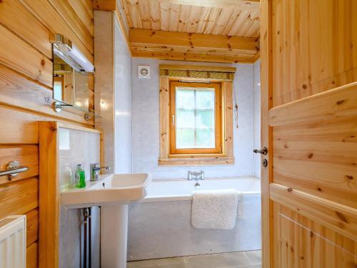 uma casa de banho com um lavatório e uma banheira em Larch em Killin