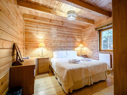 - une chambre avec un lit dans une cabane en bois dans l'établissement Larch, à Killin