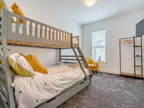 a bedroom with two bunk beds and a yellow chair at Wynbec Cottage in Esh