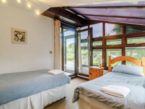 two beds in a room with a window at Silver Waters in Wroxham