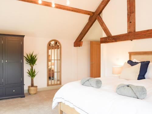a bedroom with a white bed and wooden beams at The Dairy - Uk34564 in Whitchurch