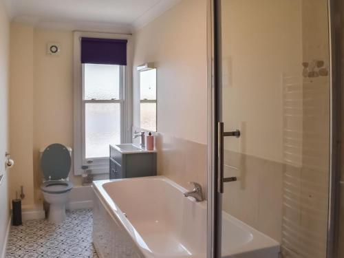 a bathroom with a bath tub and a toilet at East Apartment in Lowestoft