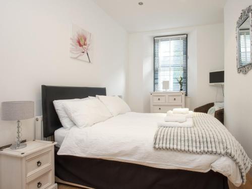 a bedroom with a large bed with white sheets at Water View in Looe