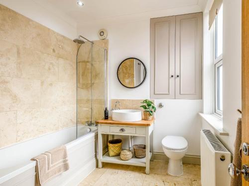 ein Badezimmer mit einer Badewanne, einem Waschbecken und einem WC in der Unterkunft Wisteria Cottage in Heacham