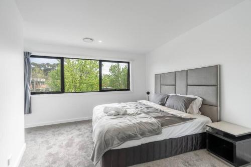 a white bedroom with a large bed and a window at Three bedroom Townhouse in O'connor ACT in Canberra