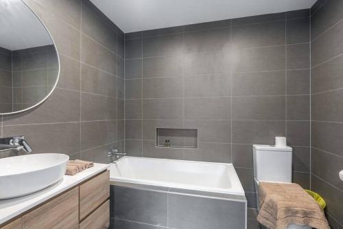 a bathroom with a tub and a sink and a mirror at Three bedroom Townhouse in O'connor ACT in Canberra