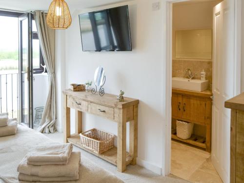 a bathroom with a sink and a tv on a wall at Riverbank Cottage in Reedham