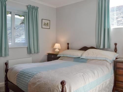 a bedroom with a bed with blue curtains and a window at Joses At The Grange in Mockerkin