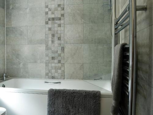 a bathroom with a tub and a shower with towels at Llwynon Cottage in Llandudno