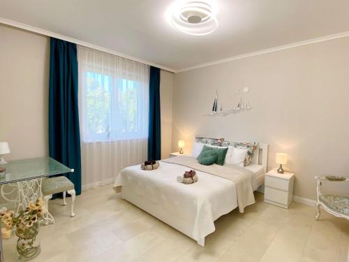 Un dormitorio con una gran cama blanca y una ventana en Luna Rossa Boutique Apartman en Balatonakali