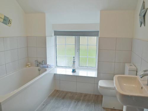 uma casa de banho com uma banheira, um WC e um lavatório. em Seascape em Craster
