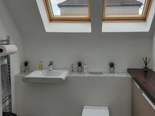 a white bathroom with a sink and a window at Rathven Parish Church Hall in Portessie