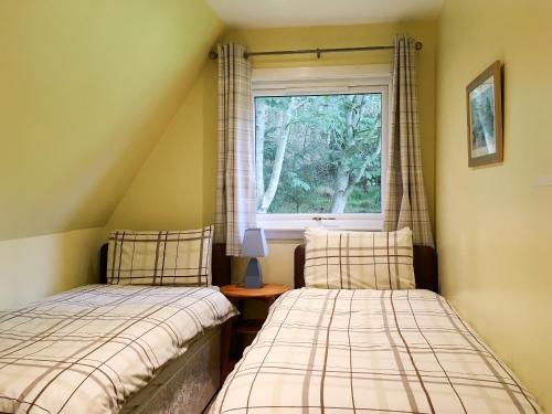 two beds in a room with a window at Thistle Lodge - Uk7051 in Glenurguhart
