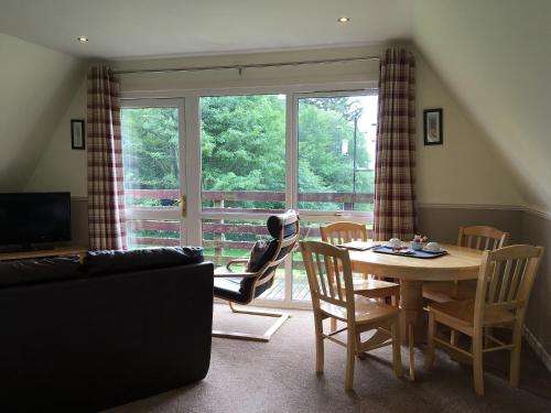 a living room with a table and chairs and a large window at Thistle Lodge - Uk7051 in Glenurguhart