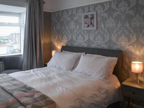 a bedroom with a white bed with a wall at Seaholme in Seahouses