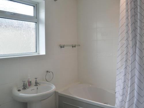 a white bathroom with a sink and a bath tub at Seaholme in Seahouses