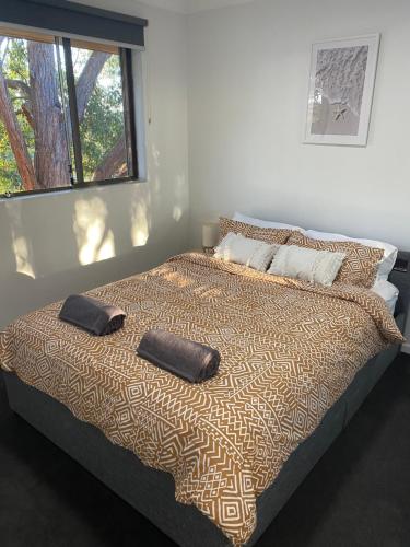 a bed with two pillows on it in a bedroom at Central Cronulla Apartment Nestled in the Treetops in Cronulla