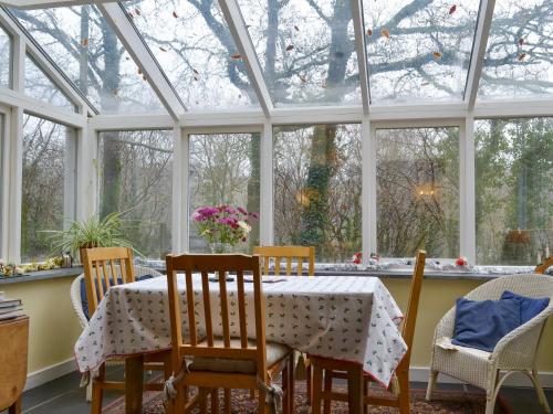 a conservatory with a table and chairs and windows at Quarrymans Cottage in Linkinhorne