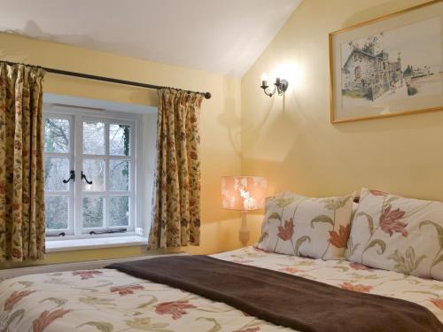 een slaapkamer met een bed en een raam bij Quarrymans Cottage in Linkinhorne