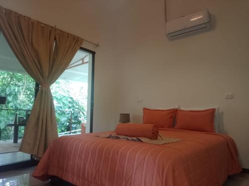 a bedroom with a bed with orange pillows and a window at Hotel San Rafael Ecolodge in San Gerardo