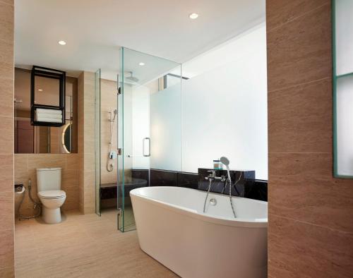 a bathroom with a white tub and a toilet at Hotel Stripes Kuala Lumpur, Autograph Collection in Kuala Lumpur