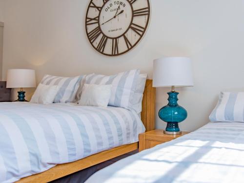 a bedroom with two beds and a clock on the wall at The Manor Coach House in Chilham