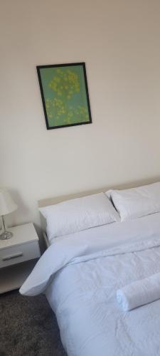 ein Schlafzimmer mit einem weißen Bett und einem Bild an der Wand in der Unterkunft 18 Decent Homes in Manchester