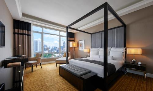 um quarto de hotel com uma cama grande e uma secretária em The Majestic Hotel Kuala Lumpur, Autograph Collection em Kuala Lumpur