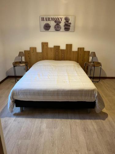 een groot bed in een kamer met 2 bijzettafels bij Les mimosas in La Bresse