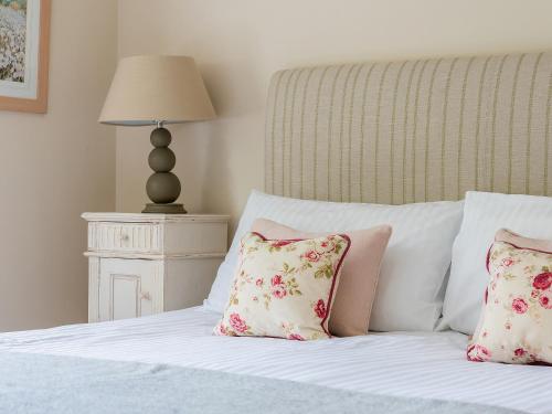 a bed with pink and white pillows and a lamp at Glaisdale in Pickering