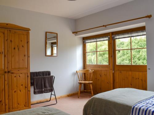 a bedroom with a bed and a chair and a window at The Cottage At Cauldcoats in Linlithgow