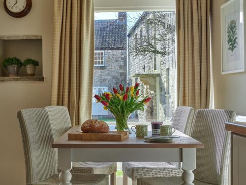 a table with a vase of flowers and a window at Glaisdale in Pickering