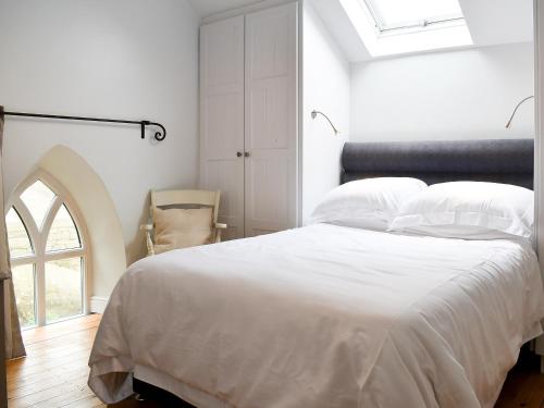 a bedroom with a white bed and a window at The Old Chapel in Ashover