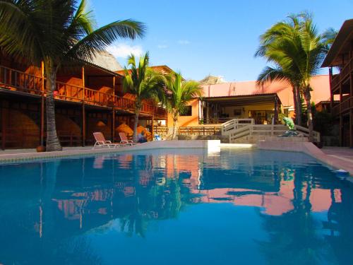 a large swimming pool with palm trees and a building at Hotel El Murique in Zorritos