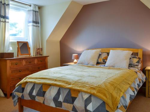 Larch Cottage في بليرغوري: غرفة نوم بسرير وخزانة ونافذة