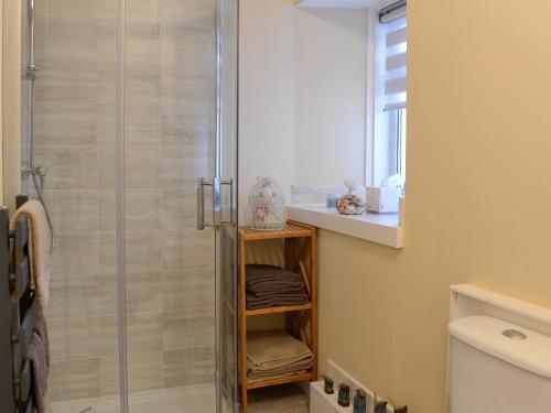 baño con ducha y estante con toallas en Larch Cottage, en Blairgowrie