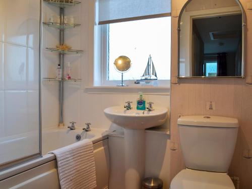 a bathroom with a sink and a toilet and a mirror at Brae Lodge in Cullen