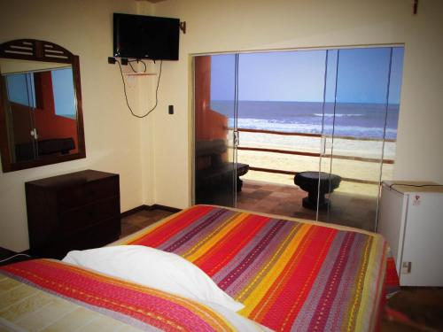 a bedroom with a bed and a view of the beach at Hotel El Murique in Zorritos