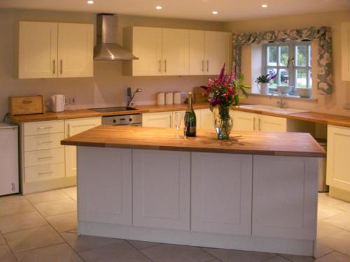 a kitchen with white cabinets and a counter with a vase of flowers at Honeysuckle Cottage in Oasby
