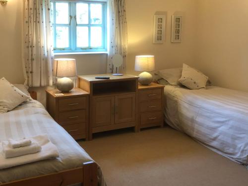 a bedroom with two beds and a desk with two lamps at Honeysuckle Cottage in Oasby