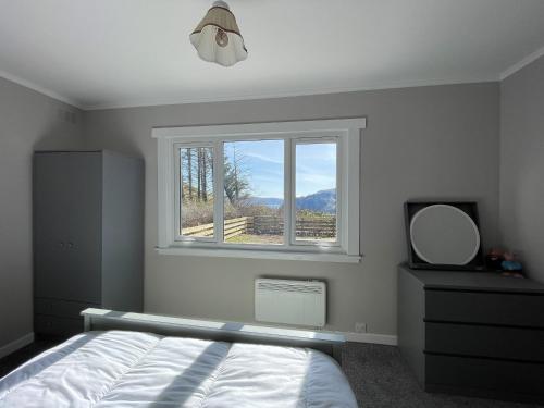 a bedroom with a bed and a window and a mirror at Greenhill in Portree